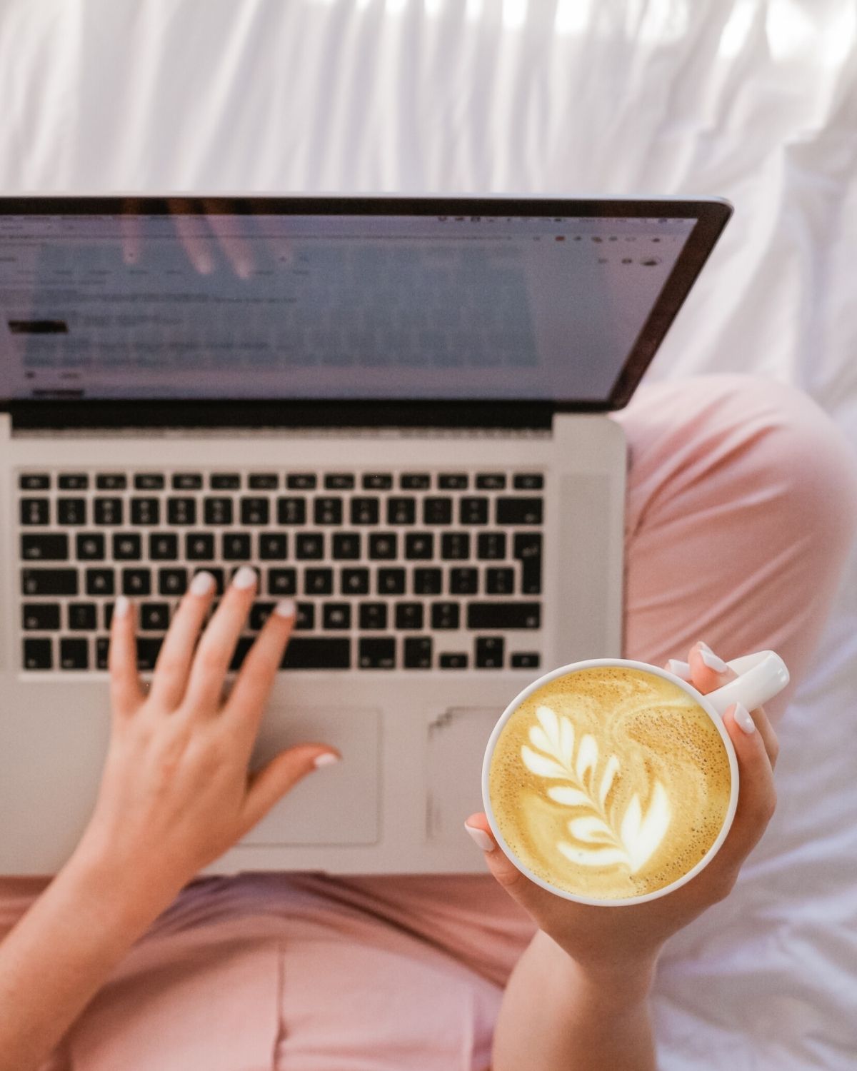woman using laptop in bed with coffee